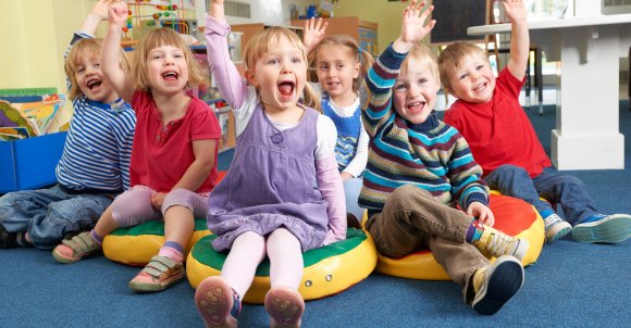 Group Of Pre School Children Answering Question In Classroom